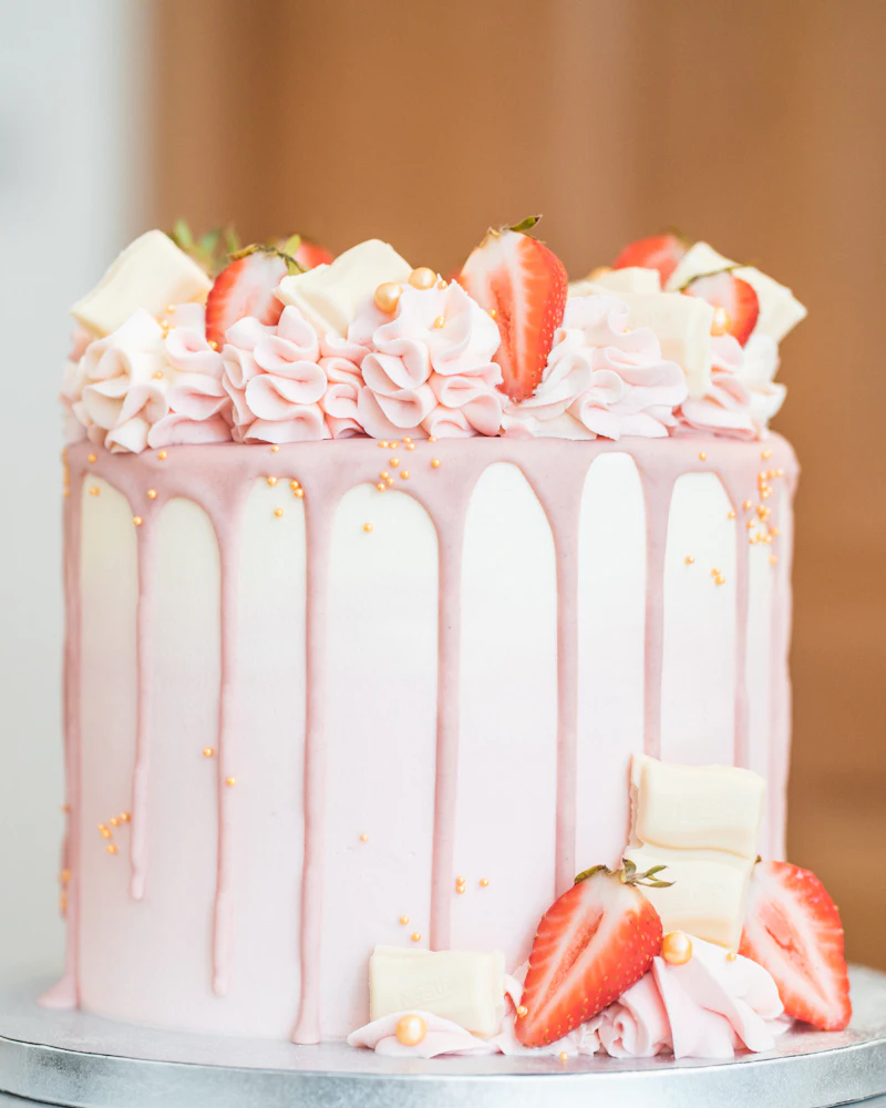 Torta con chorreado rosa, crema y frutillas