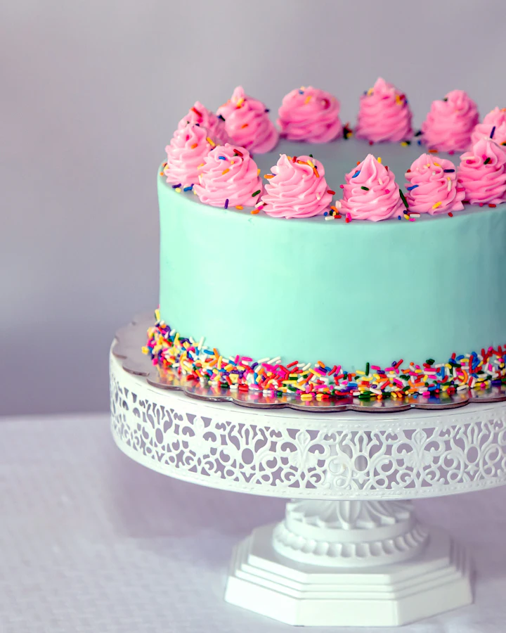 Torta celeste con rosetas rosas sobre una base blanca
